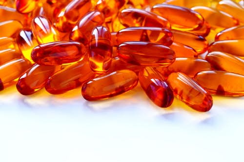 Biological additives to food, vitamins for a healthy lifestyle, capsules an omega 3 with cod-liver oil, transparent orange color an embankment on a light background close up (Biological additives to food, vitamins for a healthy lifestyle, capsules an